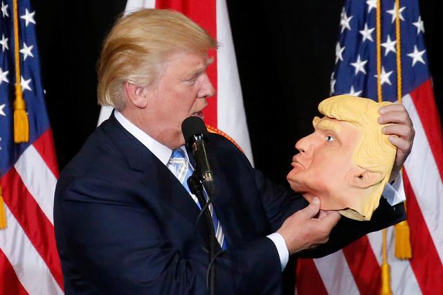 Republican presidential nominee Donald Trump looks at a mask of himself as he speaks during a campaign rally in Sarasota, Florida. (REUTERS)