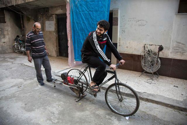 Rahmo (left) checks the state of the bicycle after it was fitted with a dynamo. (AFP Photo)