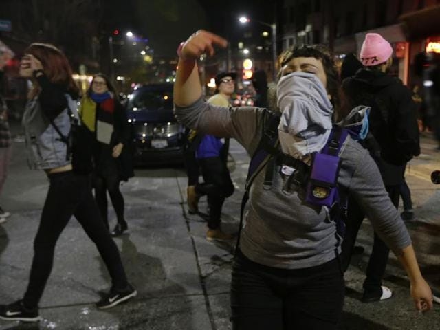 Protesters march past burned garbage in downtown Oakland, California. President-elect Donald Trump’s victory set off multiple protests(AP Photo)