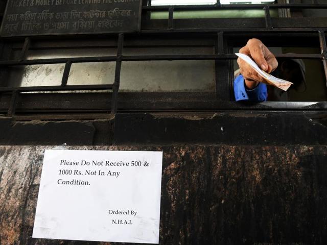 An Indian toll plaza employee receives cash above a posted notice not to receive 500 and 1000 rupee notes. (AFP Photo) An Indian toll plaza employee receives cash above a posted notice not to receive 500 and 1000 rupee notes. (AFP Photo)