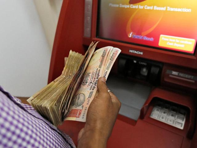 A customer deposits 1000 and 500 Indian rupee banknotes in a cash deposit machine at bank in Mumbai.(Reuters Photo)