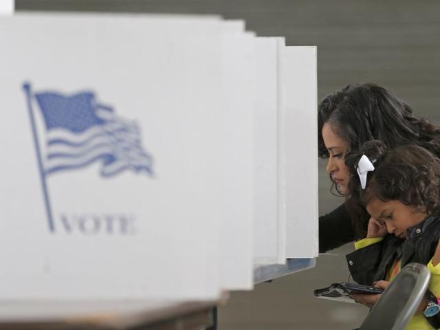 Betsy Argueta holds her daughter Isabella, 2, as she votes in the US presidential election at the National Guard Armory in Smithfield, North Carolina. (REUTERS) Betsy Argueta holds her daughter Isabella, 2, as she votes in the US presidential election at the National Guard Armory in Smithfield, North Carolina. (REUTERS)