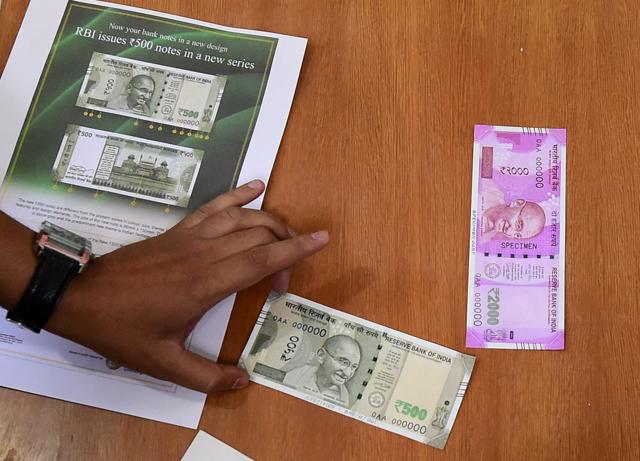 An RBI official displays the newly issued rupees 500 and 2000 notes at Reserve Bank of India headquarters in Mumbai on Wednesday. (PTI Photo) An RBI official displays the newly issued rupees 500 and 2000 notes at Reserve Bank of India headquarters in Mumbai on Wednesday. (PTI Photo)