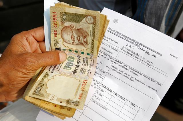 A person stands with his documents in a queue outside a branch of the State Bank of India as people wait to exchange old high denomination bank notes in Old Delhi. (Reuters Photo) A person stands with his documents in a queue outside a branch of the State Bank of India as people wait to exchange old high denomination bank notes in Old Delhi. (Reuters Photo)