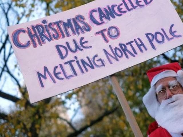 A man dressed as Santa Claus displays a placard during a rally calling for action on climate change in New York on November 29, 2015, a day before the start of the COP21 conference in Paris.(AFP)