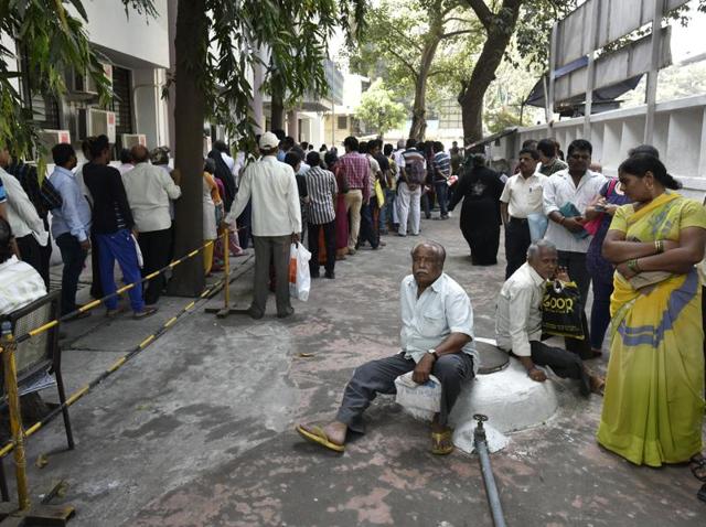 People rest after standing in a queue for long outside a bank in Ghatkopar. (Arijit Sen/HT PHOTO) 