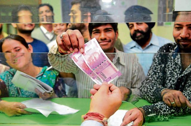 A migrant labourer receiving new currency notes of Rs 2000 from a bank in Jalandhar on Thursday. (Pardeep Pandit/HT Photo)