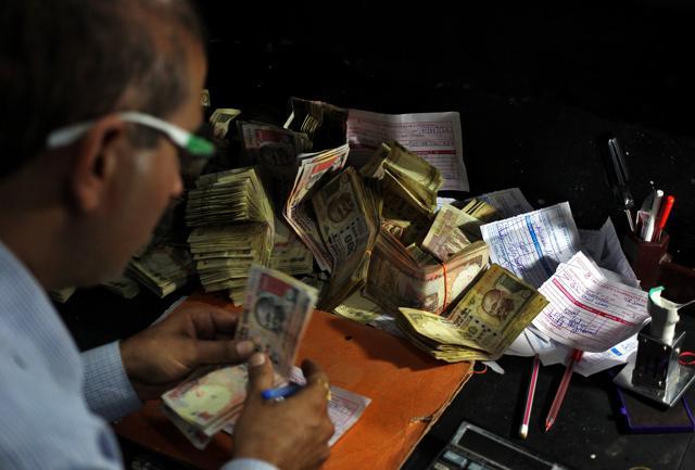 A cashier counts 500 and 1000 Indian rupee banknotes inside a bank. (REUTERS) A cashier counts 500 and 1000 Indian rupee banknotes inside a bank. (REUTERS)