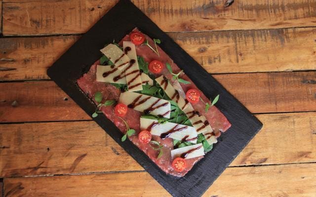 The paper-thin slices of tenderloin carpaccio, served on a rectangular black tile, are fresh and unencumbered by unnecessary flavourings. (Bhushan Koyande / HT Photo)