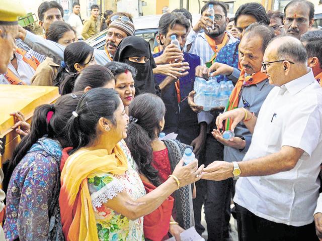 BJP state president Ashok Parnami offers water bottles to people standing in a queue outside a bank in Raja Park area in Jaipur on Sunday. (HT Photo) BJP state president Ashok Parnami offers water bottles to people standing in a queue outside a bank in Raja Park area in Jaipur on Sunday. (HT Photo)