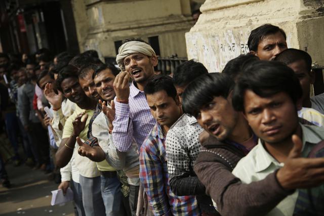 A man gestures to convey that he has no money to buy food, as he stands in a queue with others to deposit and exchange discontinued currency notes outside a bank in New Delhi.(AP)