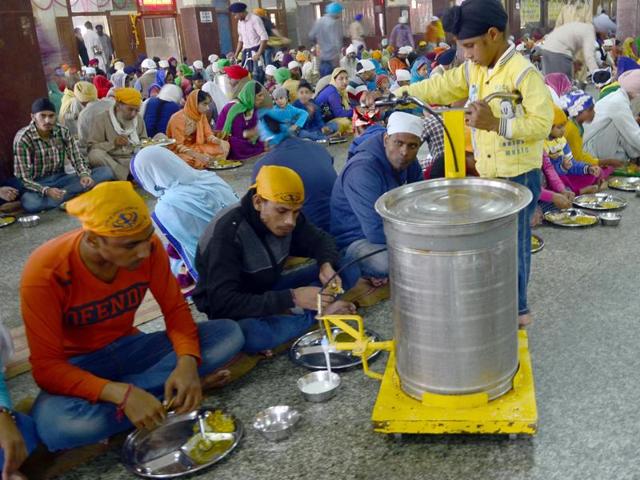 A boy dispenses food for langar (community kitchen) at the Golden Temple on the birth anniversary of Guru Nanak Dev, in Amritsar on Monday. (Sameer Sehgal/HT Photo)