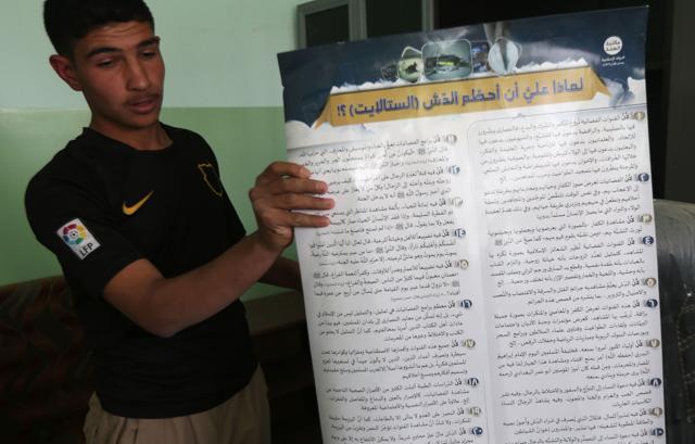 An Iraqi youth shows a placard printed out by the Islamic State (IS) group, explaining why people shouldn't use satellite dishes, as he visits his school in the village of Jarif, some 45 kilometres south of Mosul. (AFP Photo) An Iraqi youth shows a placard printed out by the Islamic State (IS) group, explaining why people shouldn't use satellite dishes, as he visits his school in the village of Jarif, some 45 kilometres south of Mosul. (AFP Photo)