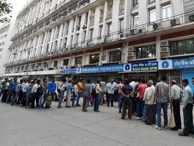 People stand outside an ATM to withdraw cash, in New Delhi.(PTI Photo)