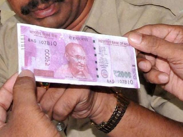 Police personnel inspect a photocopy of a Rs 2000-note, which was given to them by a vegetable seller.(PTI File Photo)