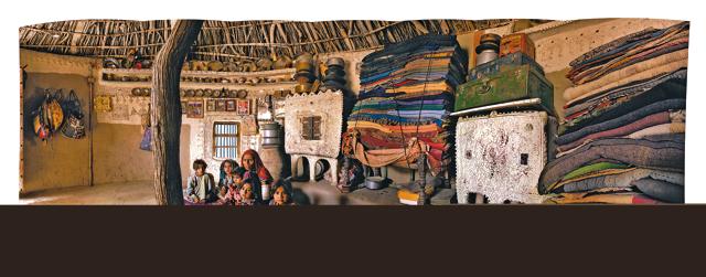 Meghwal Bhunga, Ludiya, Kutch, Gujarat. Kalka Bhura with her five daughters. Her traditional Meghwal home is a beautiful mud and clay-daubed circular house frescoed and painted inside and out with geometric patterns and inset with pieces of mirror. On the traditional cupboards made out of clay for storing foodgrain are piled the coarse kharad rugs which Kalka has been quilting herself from the time she was six years old. Kalka’s husband Bhanwar Bhura woos tourists to their home to buy the embroidered mirror-embellished cushion covers that his wife and their eldest daughter make. (Amit Pasricha) Meghwal Bhunga, Ludiya, Kutch, Gujarat. Kalka Bhura with her five daughters. Her traditional Meghwal home is a beautiful mud and clay-daubed circular house frescoed and painted inside and out with geometric patterns and inset with pieces of mirror. On the traditional cupboards made out of clay for storing foodgrain are piled the coarse kharad rugs which Kalka has been quilting herself from the time she was six years old. Kalka’s husband Bhanwar Bhura woos tourists to their home to buy the embroidered mirror-embellished cushion covers that his wife and their eldest daughter make. (Amit Pasricha)