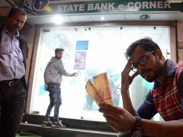 A man sits with Rs 500 notes withdrawn from an ATM after PM Narendra Modi announced to cease Rupees 500 and 1000 currency notes in Bhopal on November 8.(PTI)