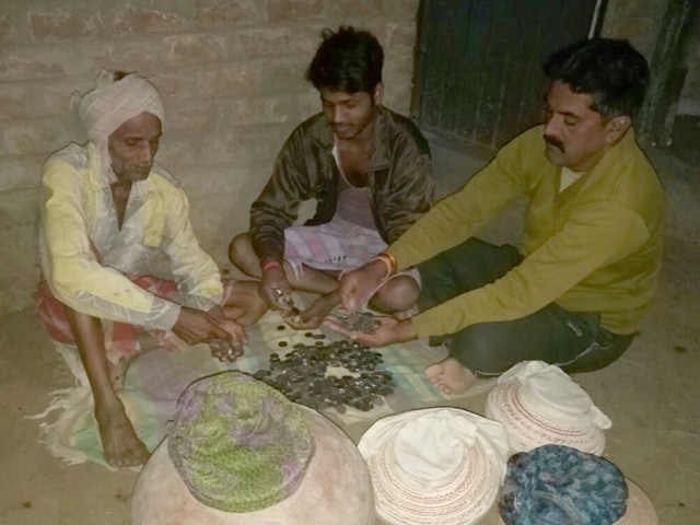 Electricity department employees and Rev Singh count the coins at the farmer’s house in Dhar district’s Kankariya village.(Shankar Mourya/HT photo)