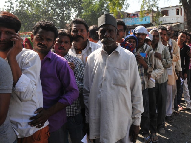 People stand in a queue outside a Central Bank of India branch at Dharampuri village on the outskirts of Indore on Tuesday. There are only three ATMs in and around the village.(Shankar Mourya/ HT photo)