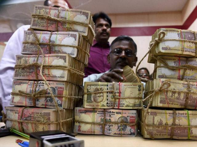 A bank employee counting the bundles of scrapped 1000 & 500 bank notes at cash counter at a Punjab National Bank branch in Chennai.(PTI Photo)