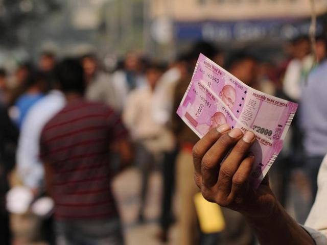 People take photos with the new Rs 2000 notes after exchanging it at a bank in Noida, Uttar Pradesh.(Burhaan Kinu/HT Photo)