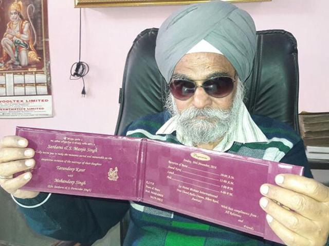 Visually impaired Manjeet Singh showing the wedding card of his daughter in Amritsar on Friday.(HT Photo)