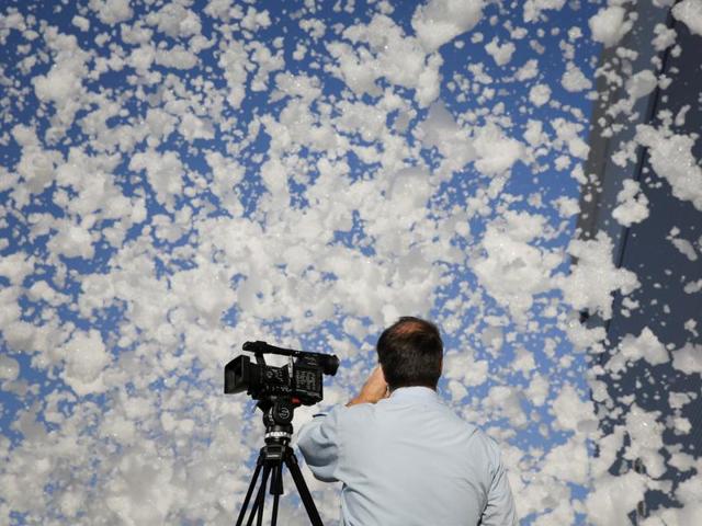 A TV cameraman films fire retardant foam blowing in the wind after a fire alarm malfunctioned in a hangar according to local media, near the San Jose airport in Santa Clara, California, US on Friday. (Reuters)