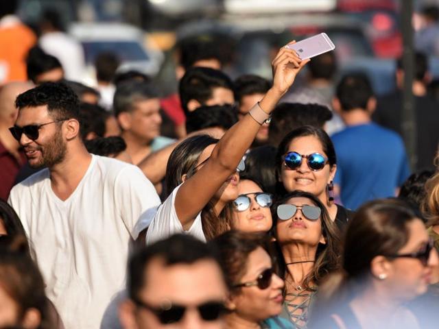 People take selfies while they wait in queues to enter the MMRDA Grounds in Bandra-Kurla Complex for the Global Citizen India concert.  (Pratik Chorge/HT PHOTO) 