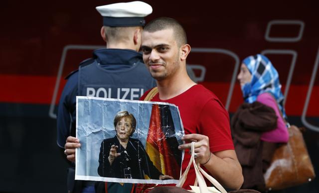 A migrant holds a portrait of German Chancellor Angela Merkel after arriving to the main railway station in Munich, Germany, in 2015. (Reuters file) A migrant holds a portrait of German Chancellor Angela Merkel after arriving to the main railway station in Munich, Germany, in 2015. (Reuters file)
