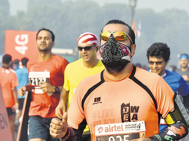 Many among the 12,000 participants at Sunday’s half marathon were seen running wearing masks, at least for the first lap, to protect from the infamous Delhi air.(Sanjeev Verma/HT Photo)