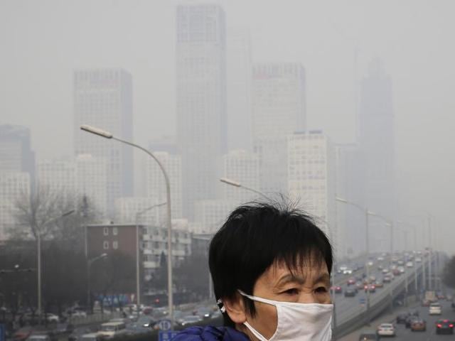 A woman wearing a mask for protection against pollution walks on a pedestrian overhead bridge as office buildings are shrouded with smog in Beijing. (AP File Photo) A woman wearing a mask for protection against pollution walks on a pedestrian overhead bridge as office buildings are shrouded with smog in Beijing. (AP File Photo)