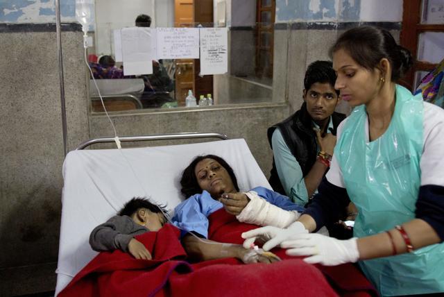 An injured passenger and her son share a bed as they are treated at a hospital in Kanpur. (AP Photo)