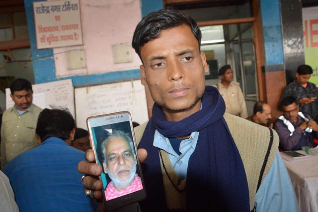A man showing a picture of his father who was travelling in Indore-Patna Express train. (PTI) A man showing a picture of his father who was travelling in Indore-Patna Express train. (PTI)
