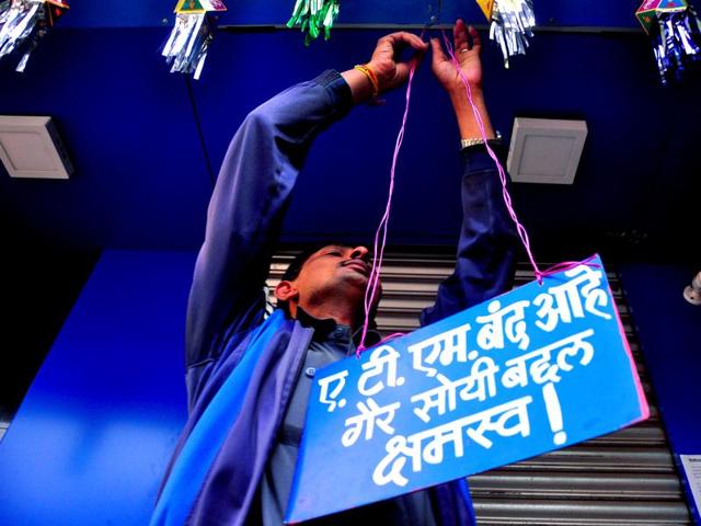 That’s all folks! A bank worker puts  up a board after an ATM in Nashik ran out of cash in the morning.  (mayur bargaje/ht photo) 