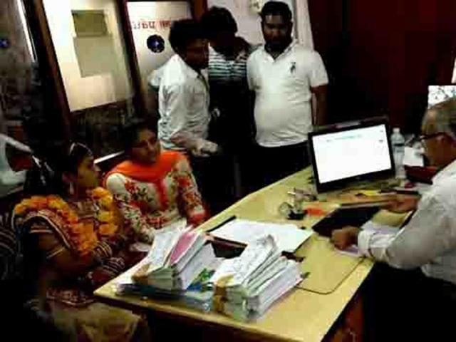Bank officials hand over the money to Arti Prajapati, who reached the bank on Sunday in bridal make-up.(HT photo)
