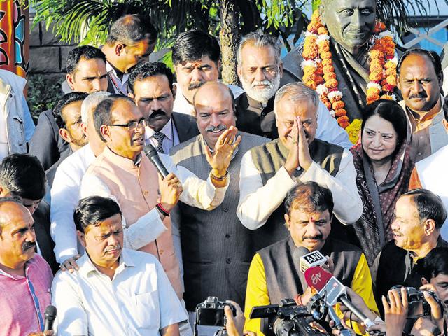CM Shivraj Singh Chouhan and state BJP president Nand Kumar Singh Chauhan offering sweets to each other at the party head office in Bhopal on Tuesday.(Mujeeb Faruqui/HT photo)