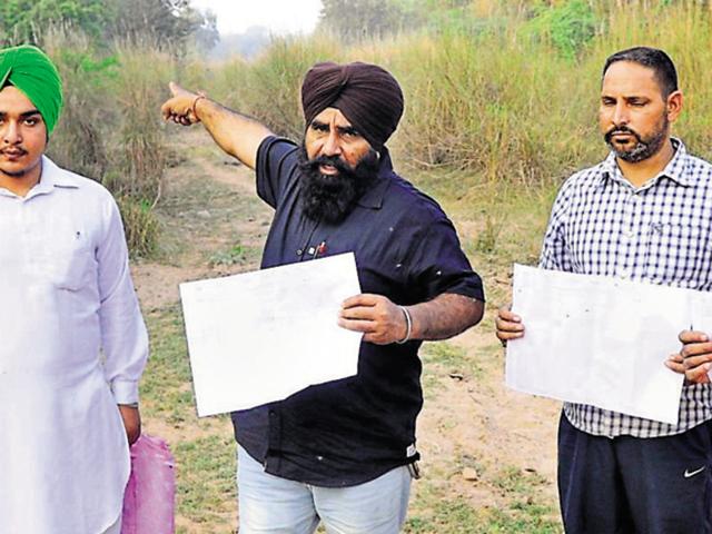 Farmers showing the revenue record with ownership rights of the SYL canal land returned to them by the Punjab government at Bibipur village in Patiala district on Tuesday. (Bharat Bhushan/HT Photo) Farmers showing the revenue record with ownership rights of the SYL canal land returned to them by the Punjab government at Bibipur village in Patiala district on Tuesday. (Bharat Bhushan/HT Photo)