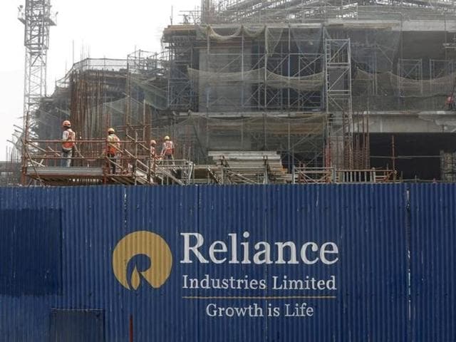 Labourers work behind an advertisement of Reliance Industries Limited at a construction site in Mumbai.(Reuters File Photo)