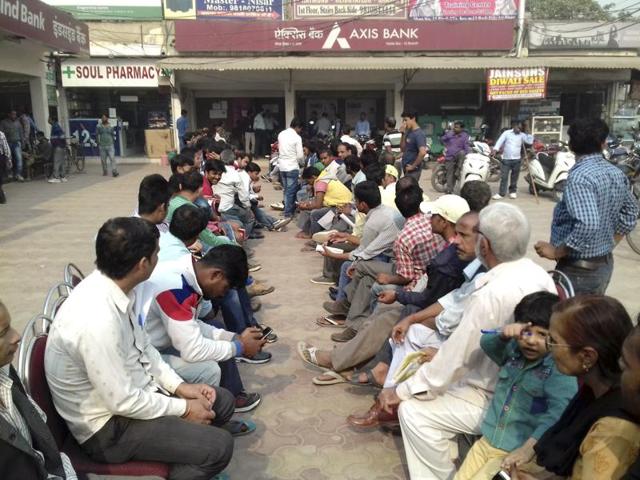 People wait outside an Axis Bank branch in Noida.(Mohd Zakir/HT Photo)