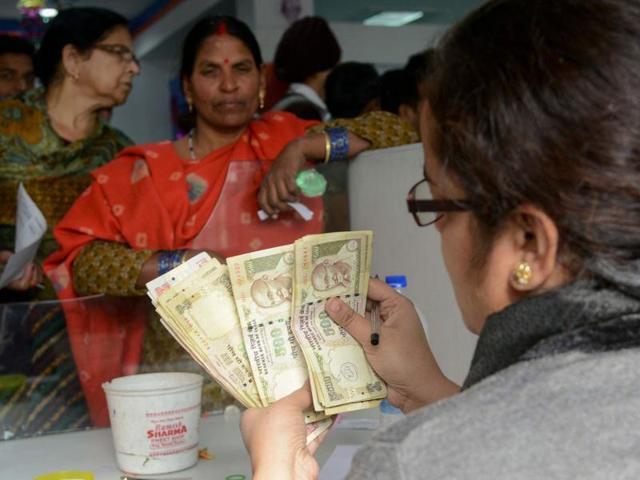 A bank employee counts notes as people gather inside a bank to deposit Rs 500 and Rs 1000 notes at a bank in Amritsar on Friday.(AFP)