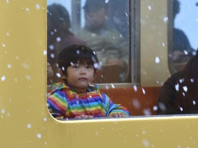 A boy looks at falling snow from a train window in Tokyo. (AFP Photo) 