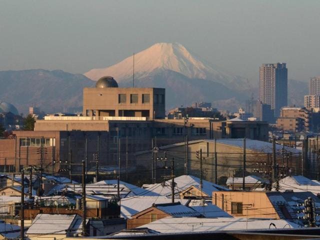 A snow-capped Mount Fuji is seen in the background as roofs of houses are covered with snow in Tokyo. (AFP Photo) 