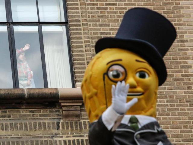 A child watches from her window as a Mr Peanut waves to the crowd. (AFP) A child watches from her window as a Mr Peanut waves to the crowd. (AFP)
