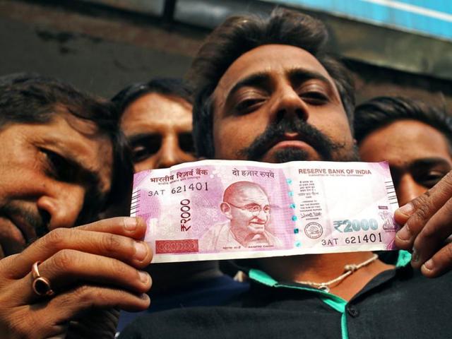 A man displays a new Rs 2000 banknote after withdrawing from a bank in Jammu.(REUTERS)