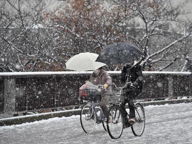 People cycle in snowfall in Tokyo. (AFP Photo) 