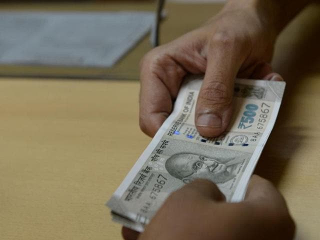 A bank staff member hands Indian 500 rupee notes to a customer in Mumbai.(AFP Photo)