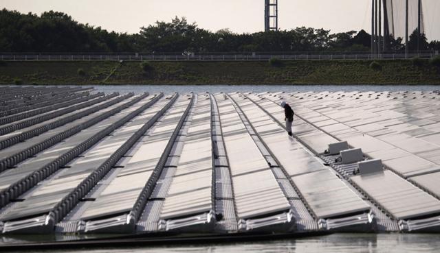A Japanese worker checking solar panels at a floating solar farm of KYOCERA company on the Yamakura dam reservoir near Ichihara city in Japan. (AFP Photo) A Japanese worker checking solar panels at a floating solar farm of KYOCERA company on the Yamakura dam reservoir near Ichihara city in Japan. (AFP Photo)