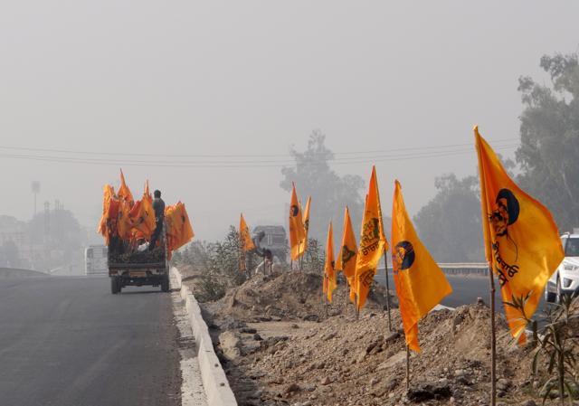 Workers installing flags carrying CM Parkash Singh Badal's photo on the Ludhiana-Ferozepur highway in Moga on Wednesday. (Parampreet Singh Narula/HT)