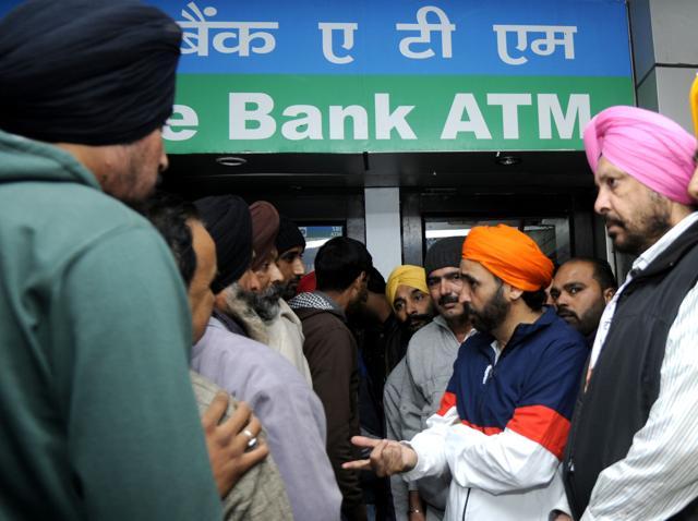 AAP MP Bhagwant Mann (centre) interacting with people in an ATM queue in Patiala on December 8. (HT File Photo)