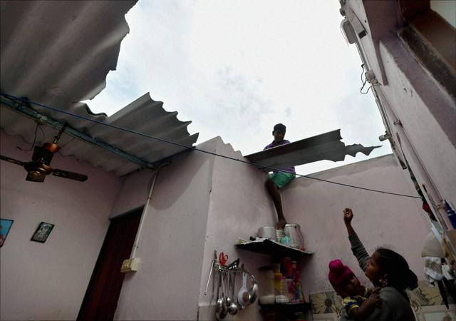 Man replacing broken roof as his wife looks on after cyclone Vardah which threw life off gear in Chennai. (PTI) Man replacing broken roof as his wife looks on after cyclone Vardah which threw life off gear in Chennai. (PTI)